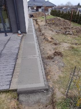 Chodnik betonowy szczotkowany wzdłuż elewacji domu jednorodzinnego