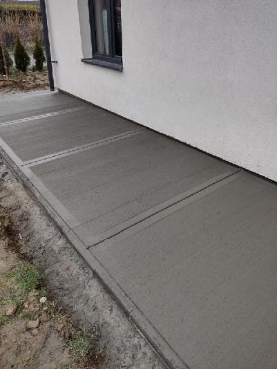 Chodnik betonowy szczotkowany z fugami dylatacyjnymi przy ścianie budynku