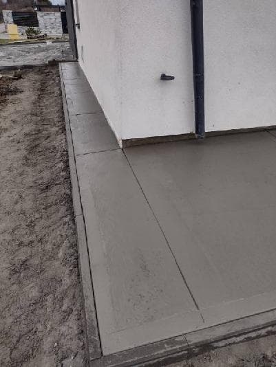 Chodnik betonowy szczotkowany wokół rury spustowej — precyzyjne wykończenie
